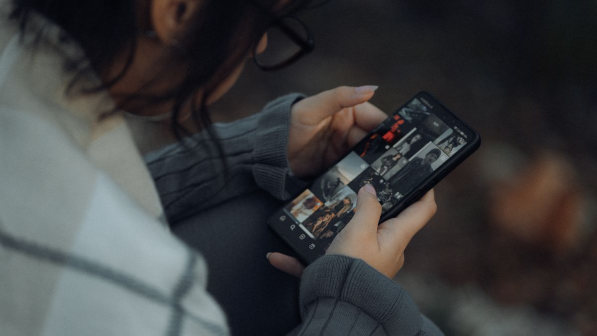 Person browsing their photo gallery on a smartphone outdoors