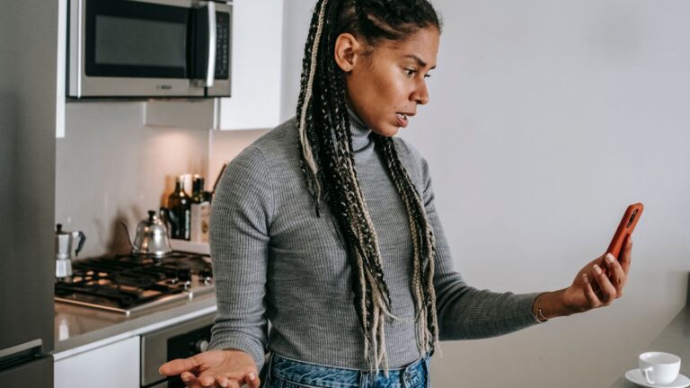 Woman looking shocked at her phone after losing photos