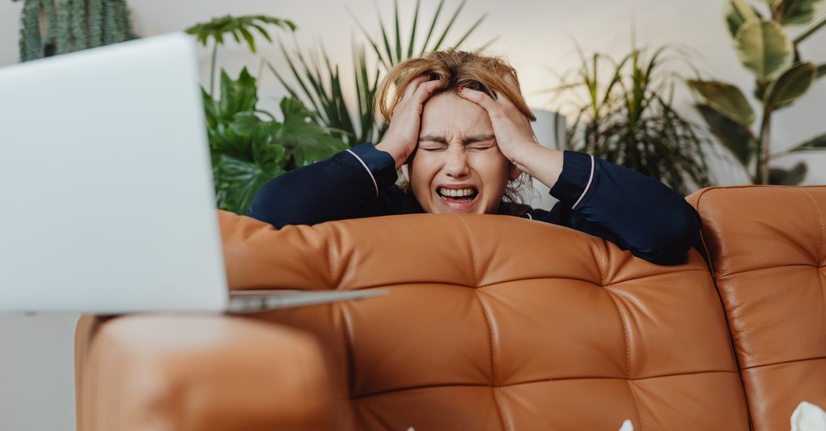 A frustrated person holding their head in front of a laptop, locked out of an email account