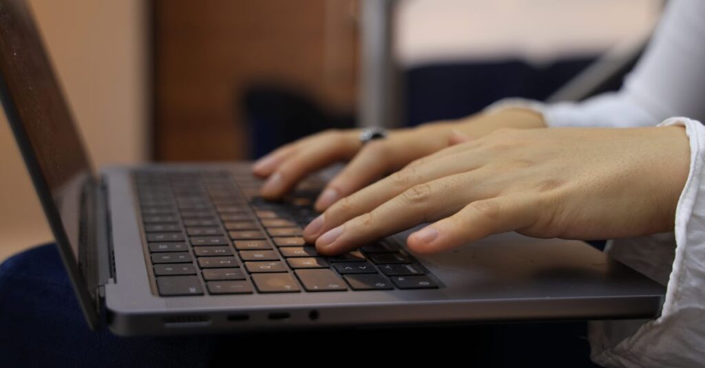 Close-up of hands typing on a laptop keyboard