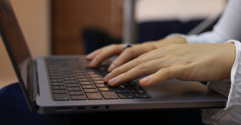Close-up of hands typing on a laptop keyboard