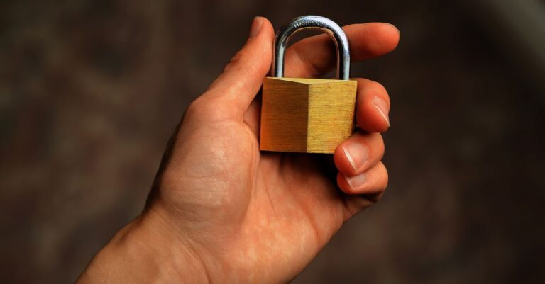 A hand holding a brass padlock, representing account security