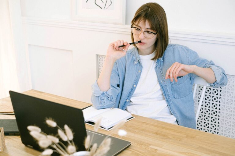 Person at a desk deciding while reviewing notes on a laptop