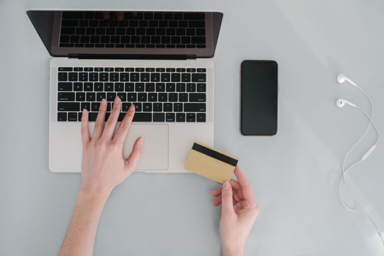 Hands using a laptop while holding a payment card