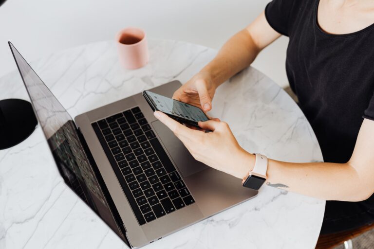 Person checking email on a phone next to a laptop